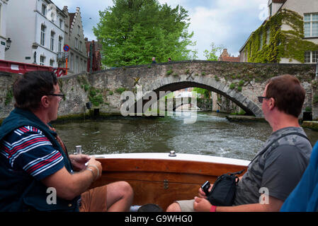 Touristen genießen eine Bootsfahrt auf den Kanälen von Brügge in Belgien. Stockfoto