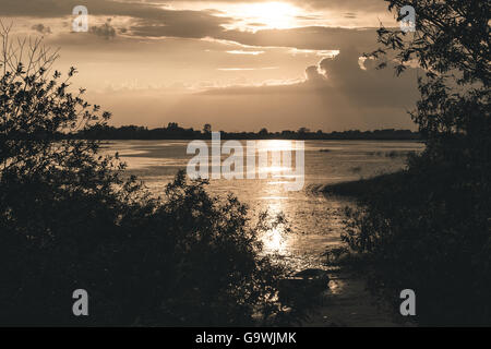 Sommer Sonnenuntergang über See und einsame Boot am Ufer Stockfoto