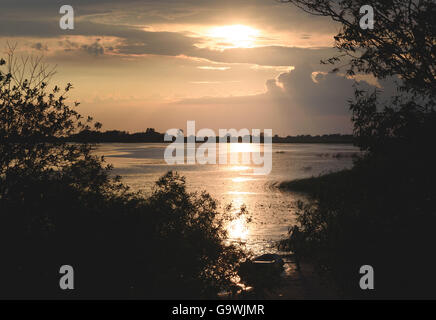 Sommer Sonnenuntergang über See und einsame Boot am Ufer Stockfoto