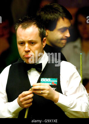 John Higgins studiert den Tisch, während Ronnie O'Sullivan während des Viertelfinalmatches bei den Snooker-Weltmeisterschaften im Crucible Theatre, Sheffield, vorbeigeht. Stockfoto