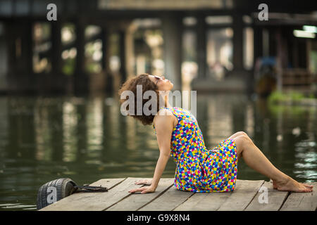 Spektakuläre junge asiatische Mädchen sitzt auf einem Fluss Dock. Stockfoto