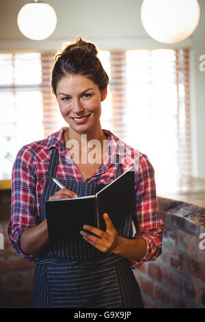 Kellnerin in einem Buch schreiben Stockfoto