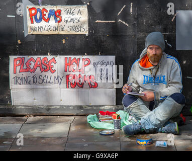 Hilfe für Obdachlose. Ein rauer Schläfer, ein sitzender Mann, der nicht bettelt, sondern Gedichte schreibt und versucht, sie zu verkaufen. Pappschilder „Please help“ (Bitte Hilfe) mit dem Leben auf den Straßen von Manchester, Großbritannien Stockfoto