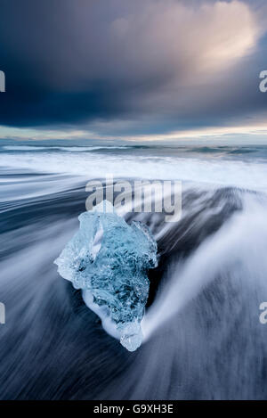 Eis auf schwarzen vulkanischen Sandstrand mit Langzeitbelichtung Wellen, Jökulsárlón, Südost-Island, Februar. Stockfoto