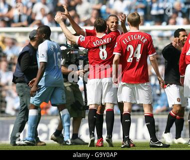 Wayne Rooney und Rio Ferdinand von Manchester United feiern nach der Letztes Pfiff, als die Sylvain Distin von Manchester City auf dem Weg ist Stockfoto