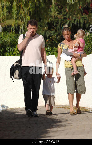 Kate McCann trägt ein Foto ihrer vermissten Tochter Madeleine, während sie Sohn Seans Hand hält und ihre Tochter Amelie trägt, während sie und Ehemann Gerry sie zu einer Kreche in Praia Da Luz, Portugal, bringen. Stockfoto