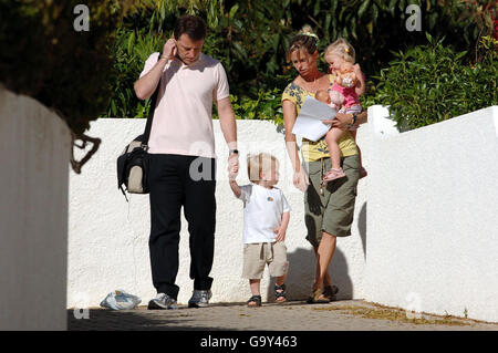 Kate McCann trägt ein Foto ihrer vermissten Tochter Madeleine, während sie Sohn Seans Hand hält und ihre Tochter Amelie trägt, während sie und Ehemann Gerry zu einer Kreche in Praia Da Luz, Portugal, gehen. Stockfoto