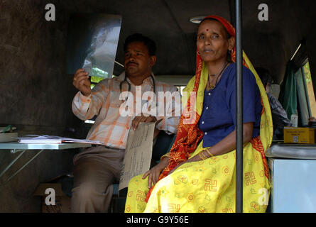 Eine ältere Frau ohne Rente oder Zugang zu medizinischer Grundversorgung, lässt eine Röntgenaufnahme von einem Arzt in einer mobilen medizinischen Einheit, die teilweise von der Wohltätigkeitsorganisation Help the Aged gesponsert wird, in Mathura im Bundesstaat Uttar Pradesh in Nordindien überprüfen. Stockfoto