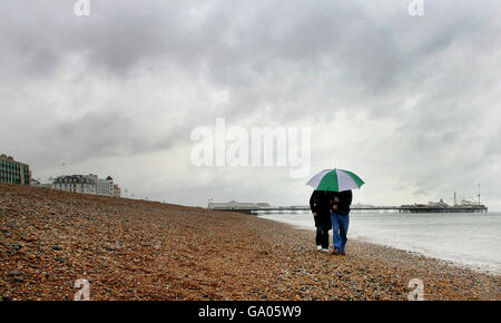 Wanderer trotzen den Elementen am Brighton Beach in Sussex, da schlechtes Wetter das Feiertagswochenende trifft. Stockfoto