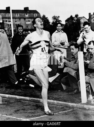 Leichtathletik - Oxford University / AAA - erste 4-minütige Meile - Iffley Road Track, Oxford. Roger Bister bricht das Band, als aufgeregt Zuschauer ihre Uhren überprüfen, um festzustellen, dass Bister die erste Meile unter vier Minuten gelaufen ist Stockfoto