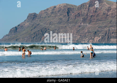 Touristen im Wasser, am Strand Playa de Famara, La Caleta de Famara, Westküste von Lanzarote, Kanarische Inseln, Spanien, Europa Stockfoto