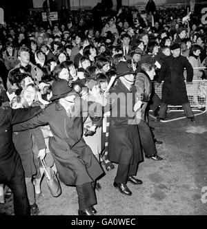 Die Fans drängen auf die zurückhaltenden verbundenen Arme einer Kette zusätzlicher Polizisten, die am Flughafen London Dienst hatten, als die Beatles von einer USA-Tournee zurückkehrten. Stockfoto