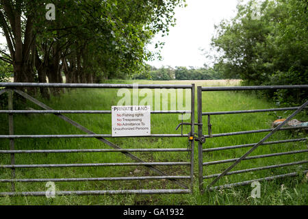 Verzinkte Tore nach einem von Bäumen gesäumten Feld und ein Zeichen besagt, dass das Privatgrundstück ist gesperrt Stockfoto