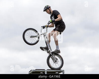Stunt-Fahrer mit seinem Stunt Bike auf dem Hinterrad auf einer hohen Plattform Stockfoto