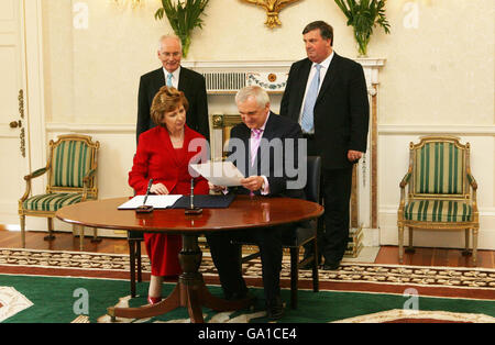 Taoiseach Berie Ahern erhält sein amtierendes Siegel von Präsidentin Mary McAleese (beide sitzen) in ihrer Residenz in Aras an Uachtarain (Büro des Präsidenten) in Dublin. Stockfoto