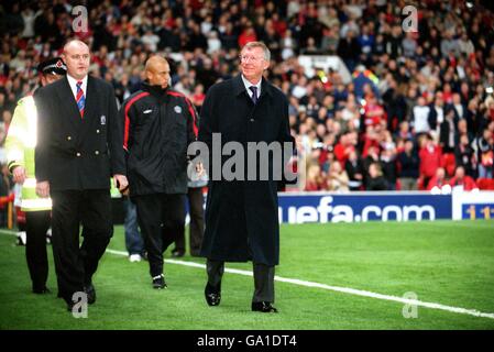 Manchester United Manager Sir Alex Ferguson (r) lächelt über die Menge, als er zu seinem Sitz begleitet wird Sicherheit Stockfoto