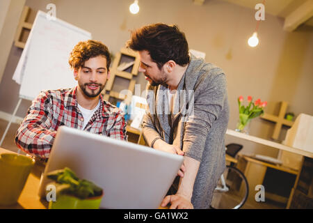 Grafik-Designer mit Laptop mit seinen Kollegen Stockfoto