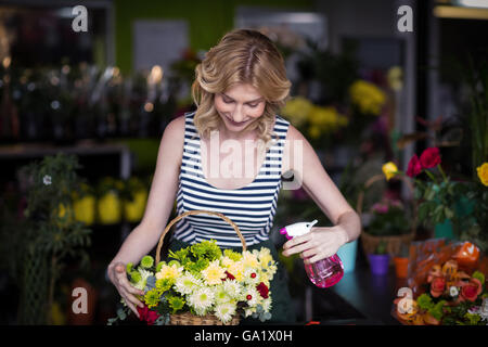 Weibliche Floristen Sprühwasser auf Blumen im Blumenladen Stockfoto