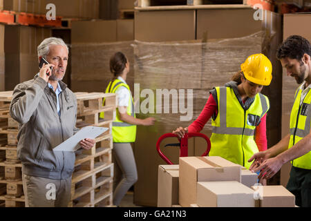 Schwerpunkt der Manager am Telefon neben den Arbeitnehmern Stockfoto