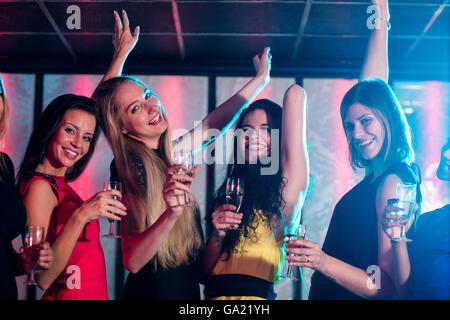 Lächelnd hält Glas Champagner beim Tanzen Freunde Stockfoto