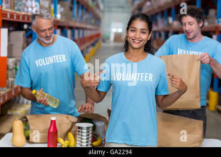 Glücklich ehrenamtliche zeigt ihr t-Shirt auf die Kamera vor ihr team Stockfoto