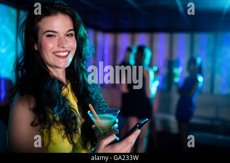 Schöne Frau mit Handy während mit cocktail Stockfoto