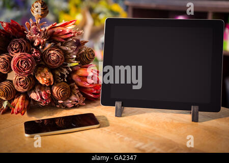 Strauß Blumen mit Smartphone und digital-Tablette auf dem Holztisch Stockfoto