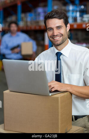 Porträt der glückliche Manager mit einem Laptop setzen auf Karton Stockfoto