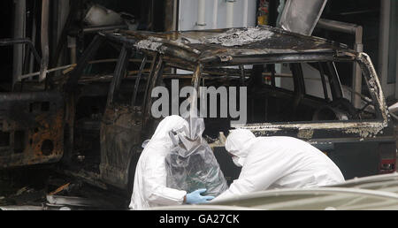 Forensische Polizeibeamte entfernen einen in Plastik gewickelten Gasbehälter vom Schauplatz des gestrigen dramatischen Angriffs auf das Terminalgebäude am Flughafen Glasgow. Stockfoto