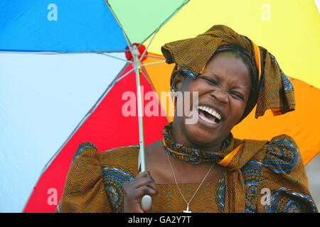 Monica Gumba aus Kenia versucht sich trocken zu halten, als das Annual Festival of World Cultures Line Up in Dun Laoghaire, Dublin, startet. Stockfoto