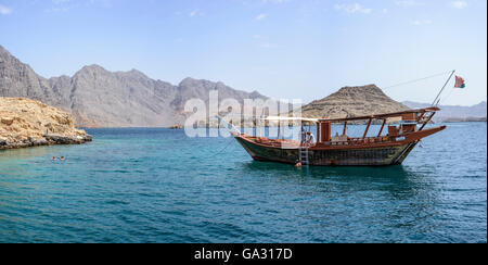 Traditionelle arabische Dhow-Anlegestelle im Fjord in Musandam mit touristischem Schnorcheln rund um das Boot, Sultanat von Oman Stockfoto