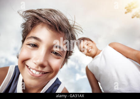 Porträt einer glücklich Jungs Kamera Lächeln und Spaß über grauen Himmelshintergrund Stockfoto