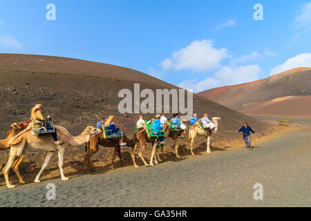 TIMANFAYA-Nationalpark, Insel LANZAROTE - 14. Januar 2015: Karawane der Kamele mit Touristen im Timanfaya Nationalpark. Kamelritt ist eine beliebte Attraktion auf der Insel Lanzarote. Stockfoto