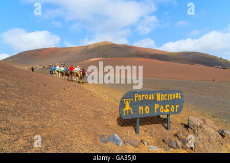 Eingangsschild zum Timanfaya Nationalpark mit Kamelkarawane in Ferne, Lanzarote, Kanarische Inseln, Spanien Stockfoto