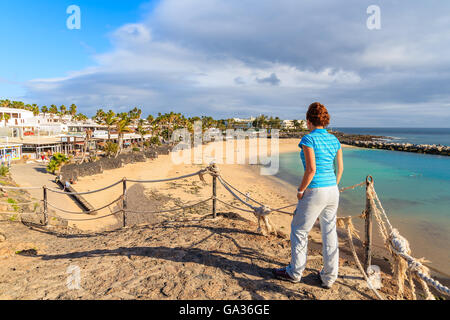 PLAYA BLANCA, LANZAROTE Insel - 16. Januar 2015: junge Frau Tourist Flamingo Strand aus Sicht betrachten. Kanarischen Inseln sind beliebtes Urlaubsziel für europäische Touristen in der Winterzeit. Stockfoto