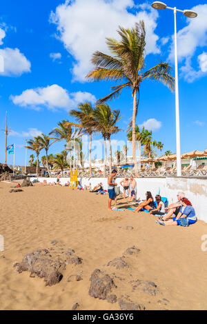 Strand PUERTO DEL CARMEN, LANZAROTE - 17. Januar 2015: Menschen am tropischen Sandstrand mit Palmen im Meer Stadt von Puerto del Carmen. Kanarischen Inseln haben das ganze Jahr Sonnenschein. Stockfoto