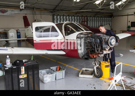 Ein Flugzeugingenieur auf der Engine von einem Leichtflugzeug in eine Wartungshalle. Stockfoto