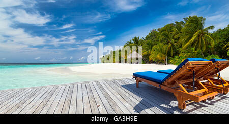 Liegestühle am Steg vor tropischen Insel Stockfoto