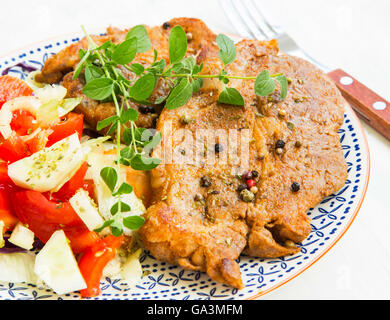 Gebratenes Schweinesteak mit Oregano, Gewürze und Gemüsesalat auf rustikale Platte Stockfoto