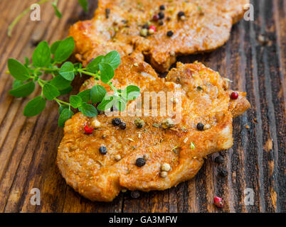 Gebratenes Schweinesteak mit Gewürzen und Kräuter Oregano auf Holzbrett Stockfoto