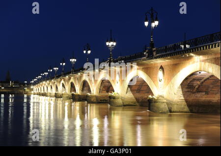 Die "Pont de Pierre" (steinerne Brücke) über den Fluss Garonne gesehen in einem Juli Nachtlicht, Bordeaux. Stockfoto