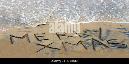 Frohe Weihnachten handschriftlich im Sand am Strand Stockfoto