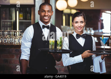 Kellner und Kellnerin hielt ein Tablett mit Glas cocktail Stockfoto