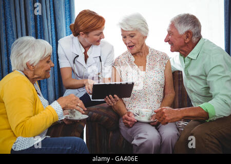 Krankenschwester zeigte und zeigt den Bildschirm eines digitalen Tablet, Rentner Stockfoto