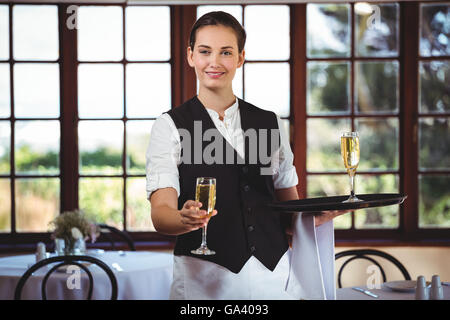 Porträt von lächelnden Kellnerin mit einem Glas Champagner Stockfoto