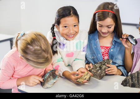 Gruppe von Kindern, die Probe Stein durch Lupe betrachten Stockfoto