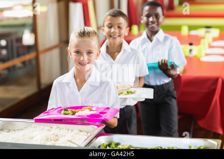 Porträt von Schulkindern mit Mittagessen während der Pausenzeit Stockfoto