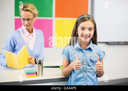 Schulmädchen zeigen Daumen im Klassenzimmer Stockfoto