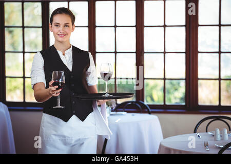 Porträt von lächelnden Kellnerin mit einem Glas Rotwein Stockfoto