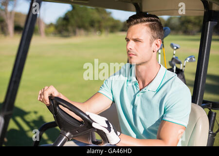 Zuversichtlich junger Mann sitzt im Golfbuggy Stockfoto